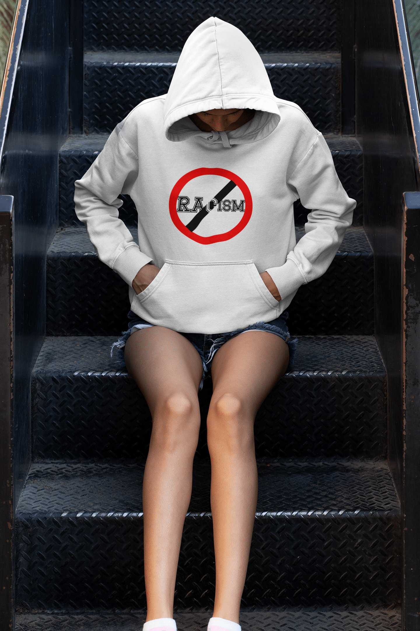 A person sitting on some steps wearing shorts and a hoodie