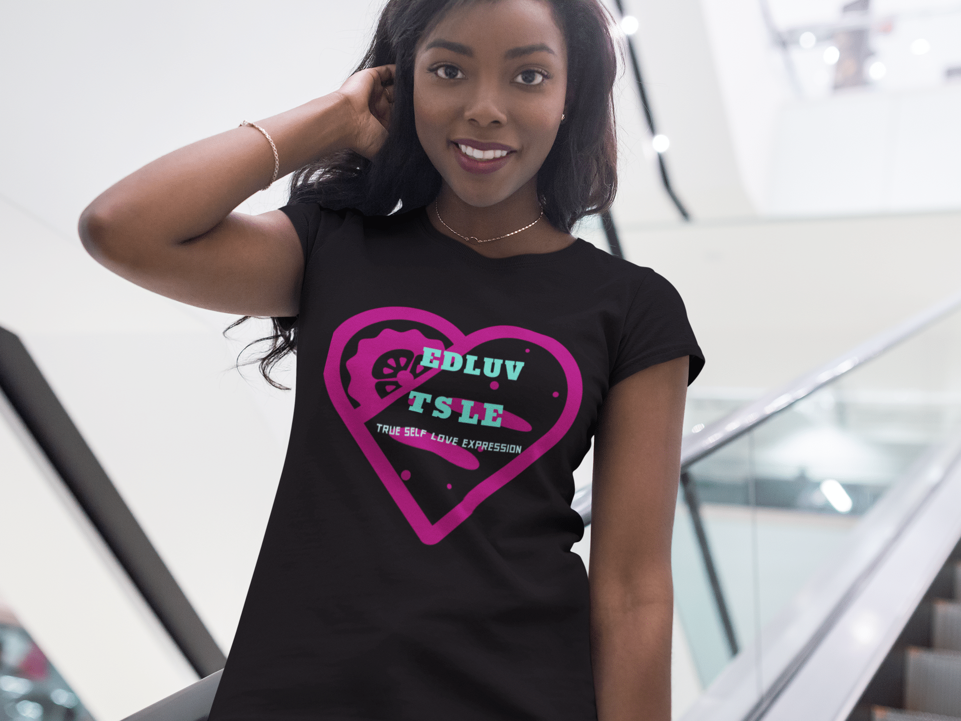 A woman wearing a black t-shirt with pink heart and words.
