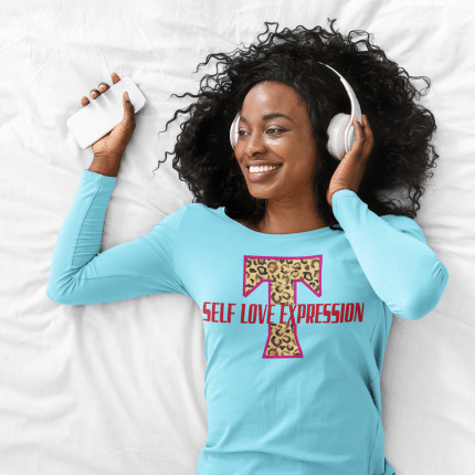 A woman laying in bed with headphones on and wearing a t shirt.