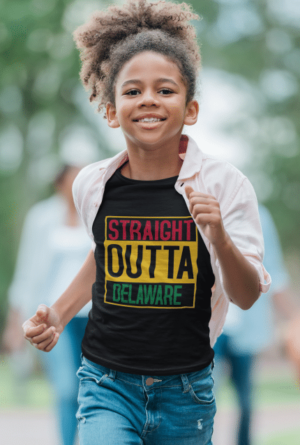 A girl running in the park wearing a shirt with a straight outta delaware design.