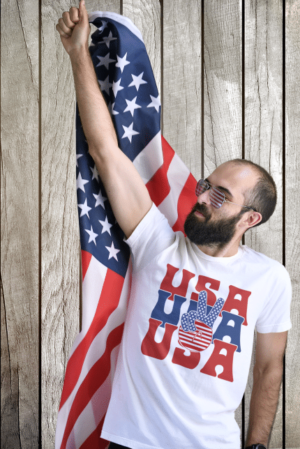 A man holding an american flag in front of a wooden wall.