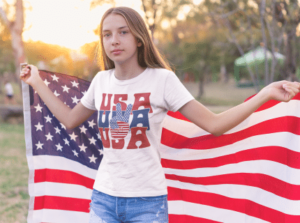 A girl in white shirt and jeans holding an american flag.