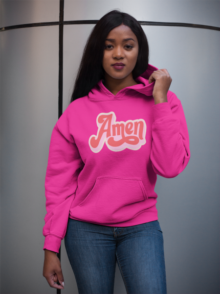 A woman in jeans and pink hoodie standing next to a refrigerator.