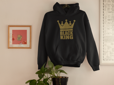 A black hoodie hanging on the wall next to a plant.