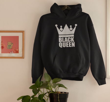 A black hoodie hanging on the wall next to a plant.