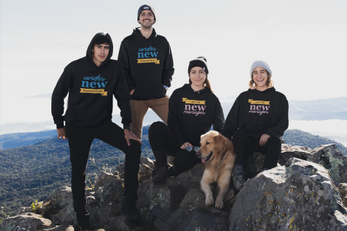 A group of people and a dog on top of a mountain.